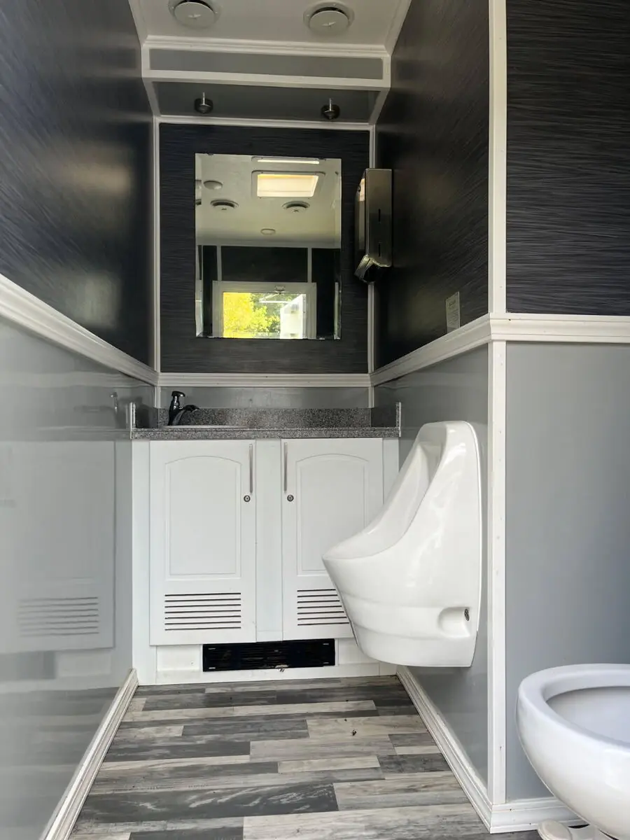 Restroom trailer room with urinal, sink and mirror